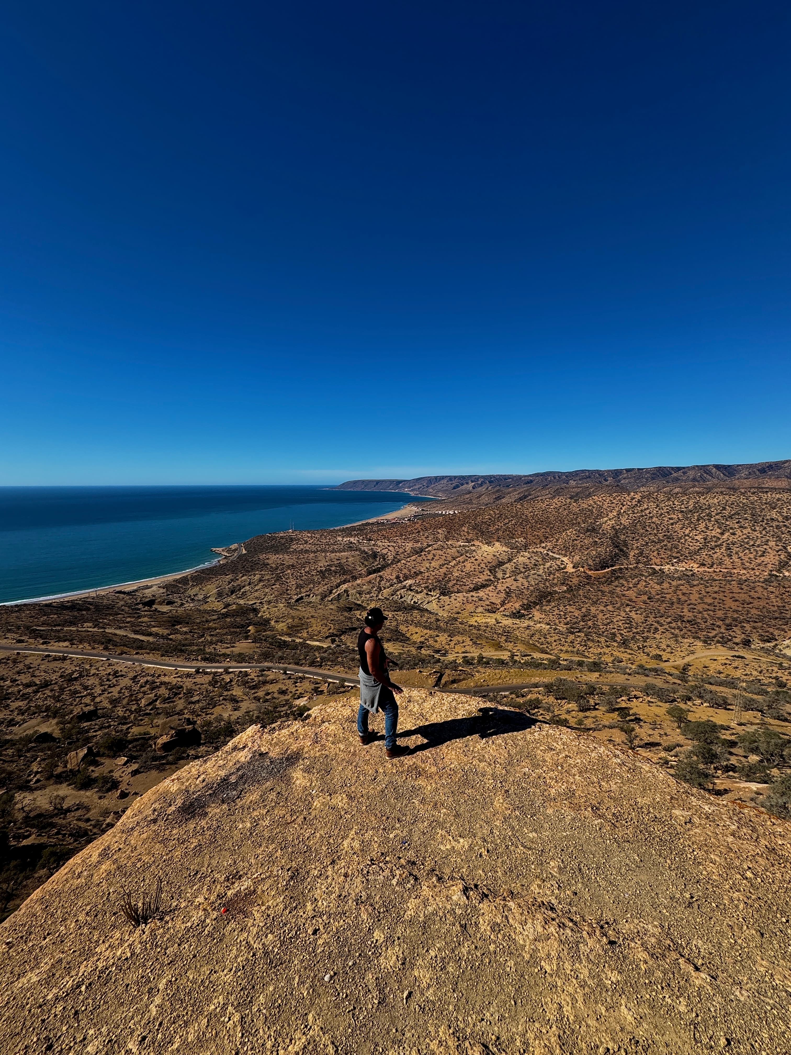 A hiker looking out over Morocco's Atlantic coastline and mountains