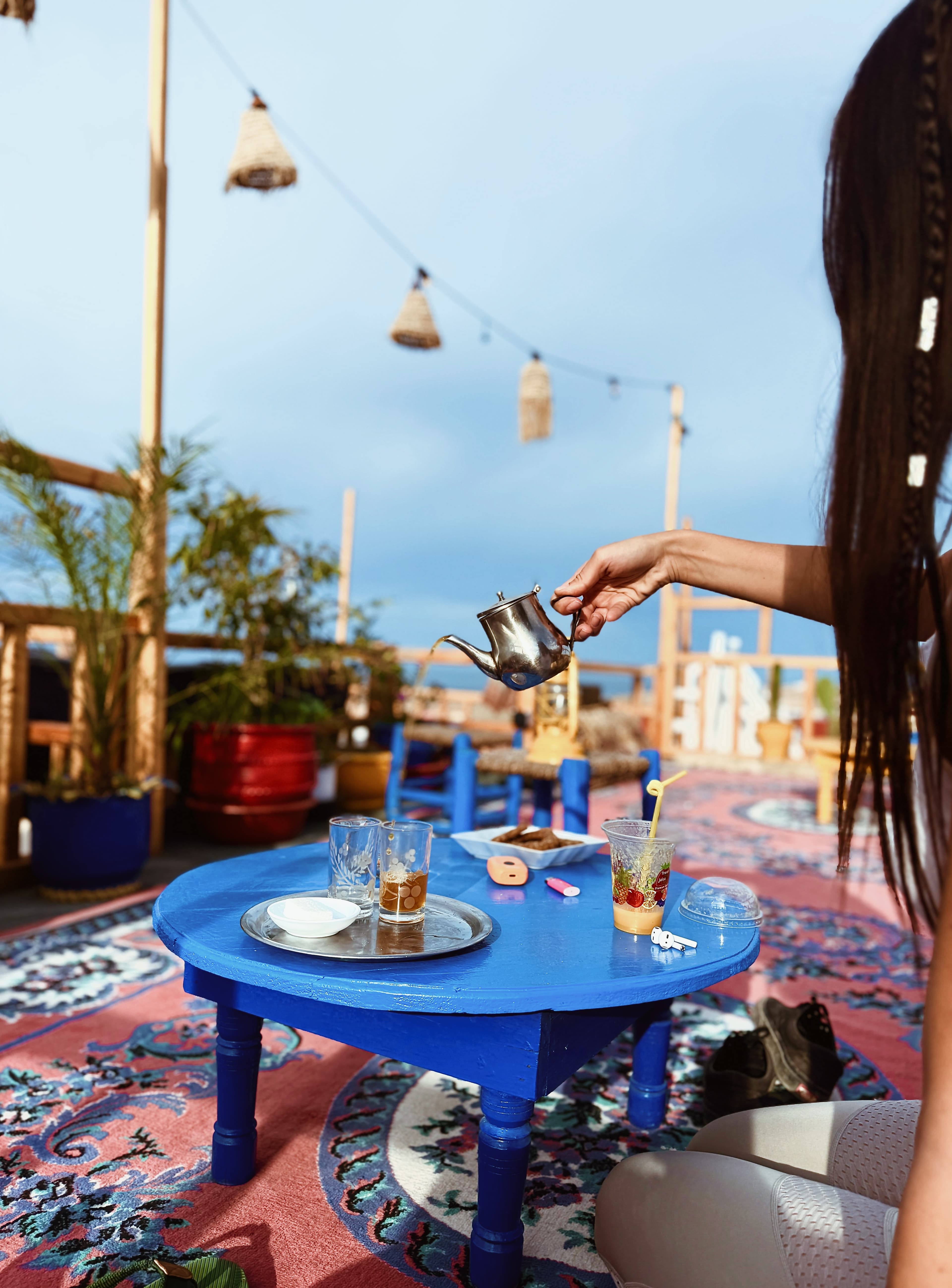 A hand pouring traditional Moroccan tea on a rooftop terrace at golden hour